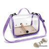 A clear plastic portable bird travel carrier with a light beige tray and purple strap.