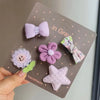 Una tarjeta hecha a mano con cinco lazos de tela morados y lavanda, incluyendo un lazo, una flor y una estrella.