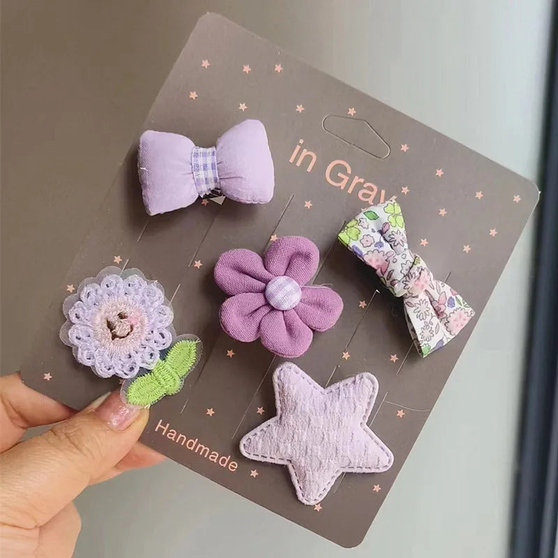 Una tarjeta hecha a mano con cinco lazos de tela morados y lavanda, incluyendo un lazo, una flor y una estrella.