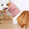 A dog wearing a pink soothing ear muff, showing the side profile of its head and neck.