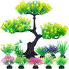 Colección de plantas de acuario artificiales realistas en tonos verdes y rosas sobre un tronco de árbol oscuro.