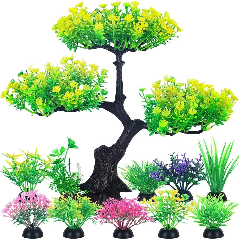 Colección de plantas de acuario artificiales realistas en tonos verdes y rosas sobre un tronco de árbol oscuro.