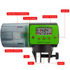 Un distributeur automatique de nourriture pour poissons, vert, avec écrans et commandes manuelles.