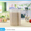 A clear airtight pet food storage container with a measuring cup is displayed on a table.