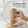 A hand adjusts the height of a hamster silent running wheel with a wooden stand to fit different cage sizes.