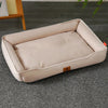A beige waterproof orthopedic dog bed with a removable cover resting on a gray carpet.