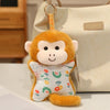 A fluffy orange monkey plush toy with large eyes and a cute expression hanging from a light beige bag.