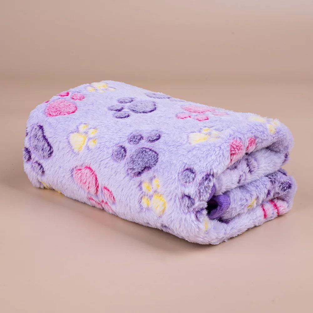 A soft purple fleece blanket featuring a pattern of pink, yellow, and purple paw prints.