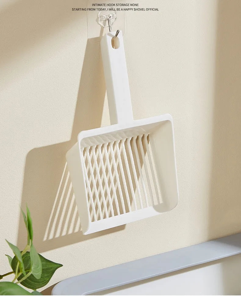 A white extra-large cat litter scoop with a hanging hook is displayed on a wall.