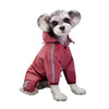 A small, fluffy dog wearing a pink waterproof raincoat with reflective stripes.