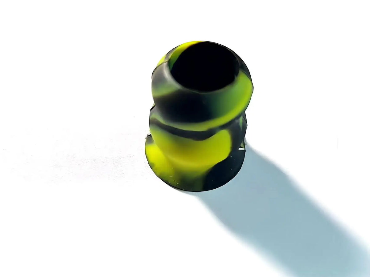 A close-up view of a silicone bat grip knob with a black and neon yellow marbled pattern.