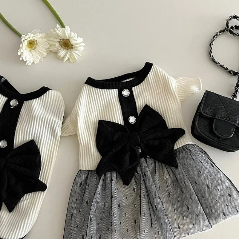 Vestido de malla blanco y negro para perros con detalle de lazo y accesorios florales.
