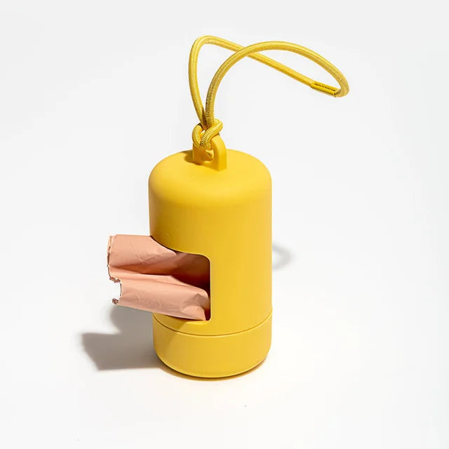 A yellow portable dog poop bag dispenser with a cardboard opening and a yellow loop handle.