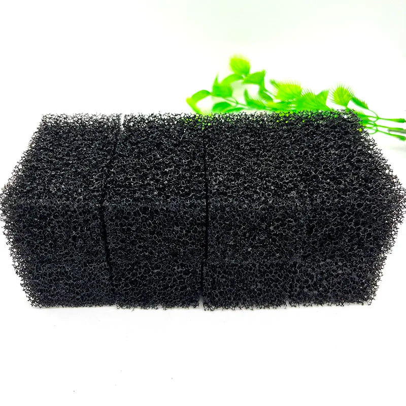 Two black aquarium bio sponge filter media blocks with green plant leaves in the background