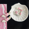 Pink and white pet hair clips shaped like hearts and angels displayed on a white dish.
