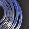 A close-up view of clear PVC flexible tubing coiled on a dark surface.