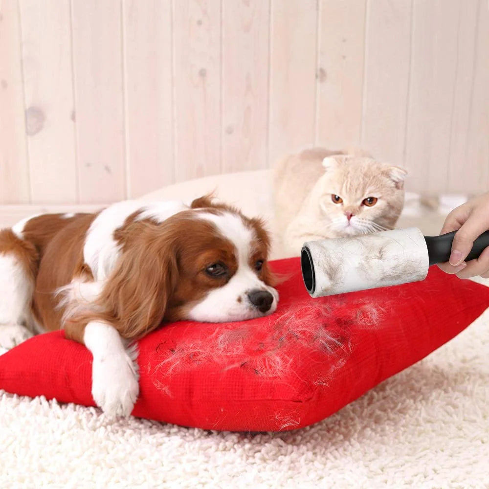 A fluffy orange and white cat is resting near a red lint roller with a black handle on a white surface.