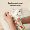 A white cat is being easily wrapped in a fabric pet swaddle designed to keep it contained.