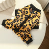 A black and orange leopard print fleece dog hoodie with animal ears lying on a white surface.