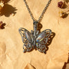 Silver butterfly pendant necklace with a chain resting on crumpled paper.