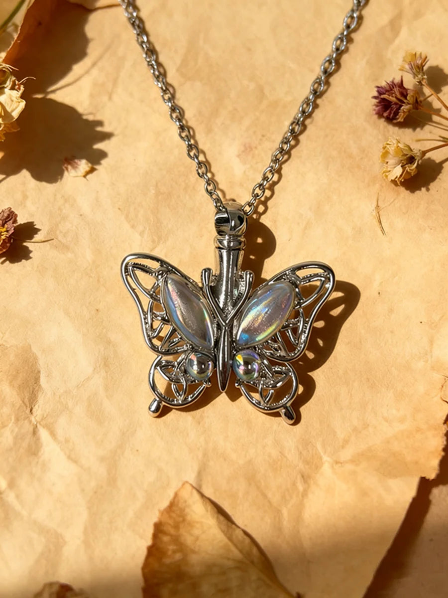 Silver butterfly pendant necklace with a chain resting on crumpled paper.