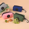 Une collection de pochettes en tissu colorées et un distributeur de sacs pour chiens sur un porte-clés vert, sur un fond clai