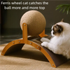 A white cat is playing with a large ball on a wooden cat scratcher featuring a sisal surface.