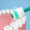 A white silicone pet toothbrush is shown cleaning teeth on a pink dental model.