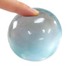 Eine Hand drückt einen glatten, durchsichtigen hellblauen Stressball.