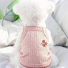 Un collar de mascota blanco y esponjoso con textura de punto rosa y ribete rojo sobre una almohada blanca.