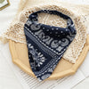 A dark blue bohemian paisley triangle head scarf displayed on a light woven fabric background.