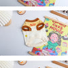 A white Korean summer pet dog vest t-shirt for small to medium breeds displayed next to a wooden frame and colorful fabric.