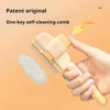 A hand holds a light beige one-key self-cleaning comb with a yellow arrow pointing to the bristles.
