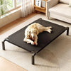 A golden retriever lies on a black mesh pet bed placed on a light rug indoors.