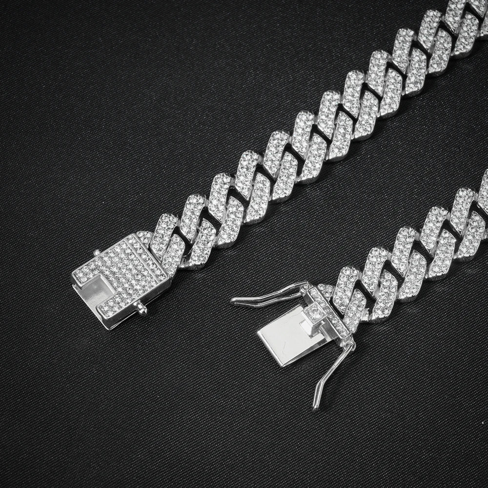 Pulsera de cadena cubana plateada adornada con diamantes de imitación claros, mostrada sobre fondo negro.