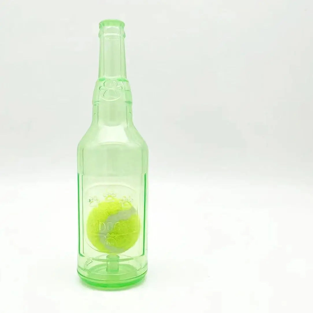 A clear green glass bottle containing a yellow squeaky tennis ball chew toy for dogs.