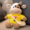 A yellow and white cow plush toy with brown accents, sitting on a light surface.