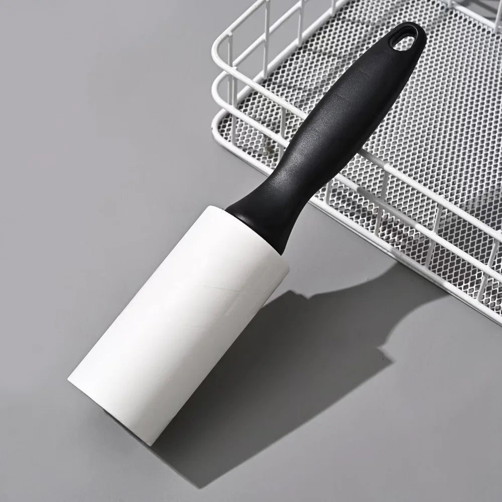 Un rodillo anti-pelusa blanco reutilizable con mango negro colocado dentro de una canasta de alambre metálico.