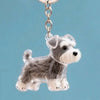 Figura de perro de plástico transparente con pelaje gris y blanco, adjunta a un anillo de llavero plateado.