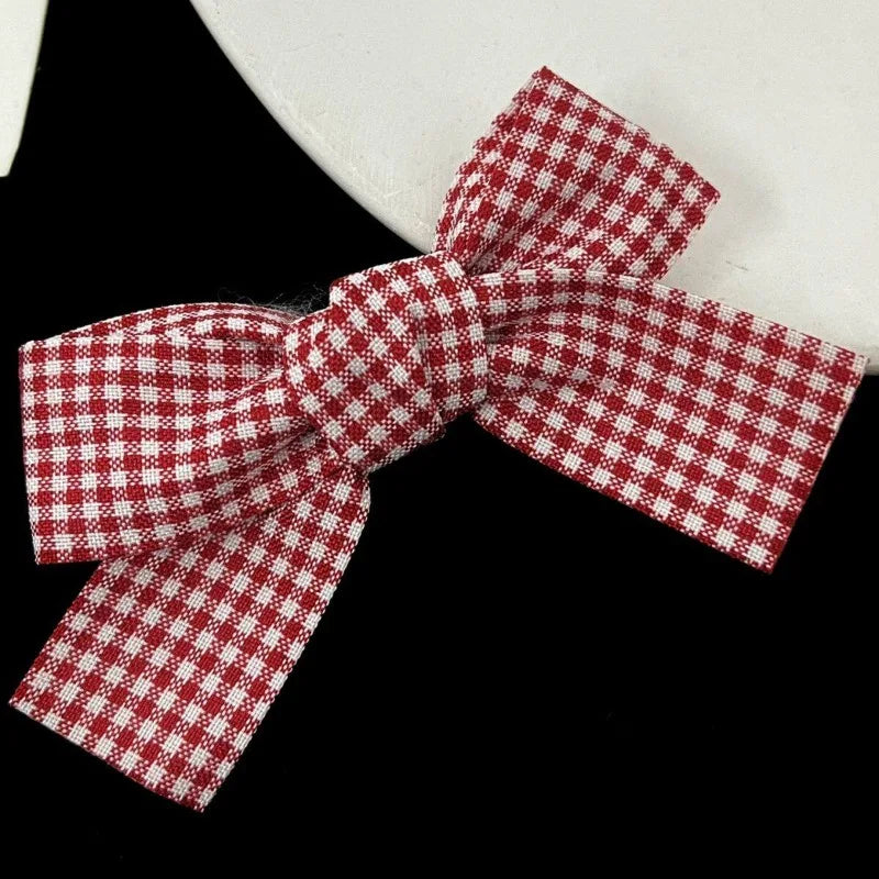 A red and white plaid fabric bow tied in a ribbon, used as hair clips.