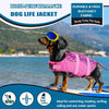 Un perro con un chaleco salvavidas rosa está de pie en una tabla de surf cerca del agua.