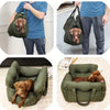 A brown dog is resting inside a green durable pet car seat with safety straps.
