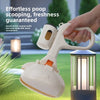 A hand is holding a white portable pet poop scooping device with an ergonomic handle, positioned near a garden light.