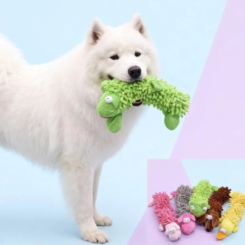 A white dog is holding a green squeaky plush chew toy.