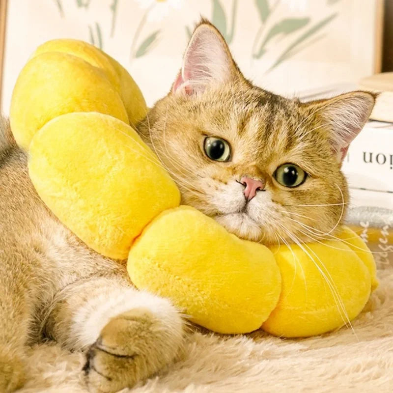 A tabby cat is lying down with a yellow plush Elizabethan collar on its neck.