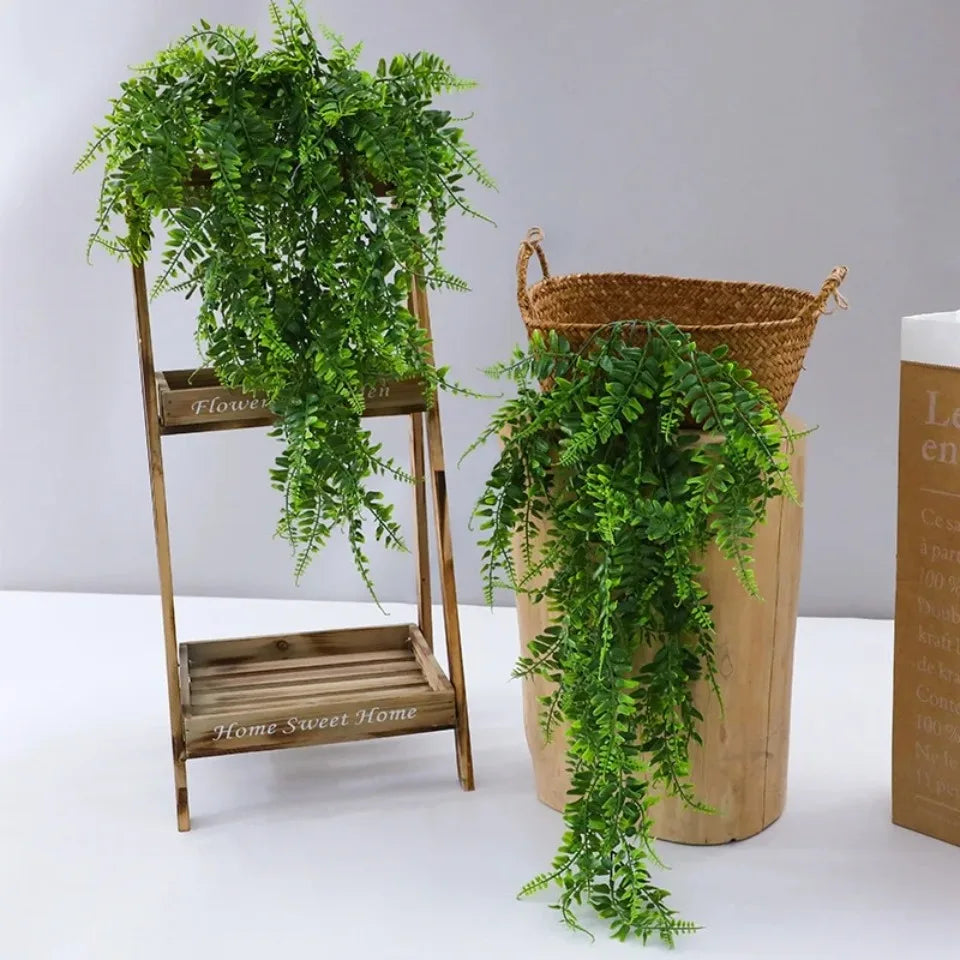 A set of four artificial Persian fern hanging vines displayed on a wooden stand and in a woven basket.