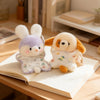 Two soft plush toys of a rabbit and a dog sitting on an open book.