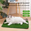 A white cat is lying on a green artificial grass pet blanket indoors.