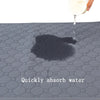 A clear liquid is dripping onto a dark gray, hexagonal pet training mat, creating a shadow.