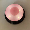 A pink recordable talking button for dog training with a circular light and small indicator LEDs.